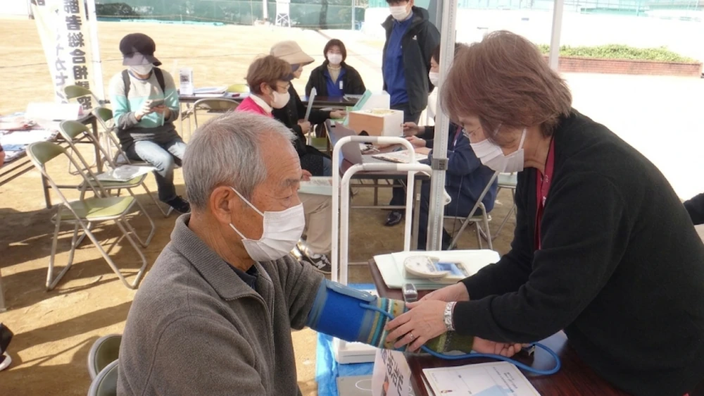 地域行事で血圧測定を行うスタッフと参加者の様子